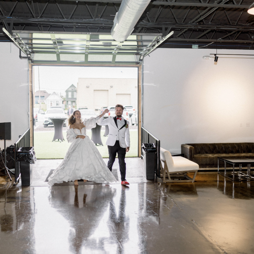 Wedding reception at Radius Indianapolis showing the bride in a white gown and groom in a white tuxedo jacket with a red bowtie making a fun grand entrance.